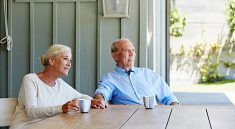 Couple de seniors qui boit un café sur sa terrasse ombragée
