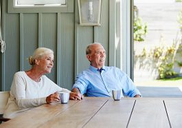 Couple de seniors qui boit un café sur sa terrasse ombragée