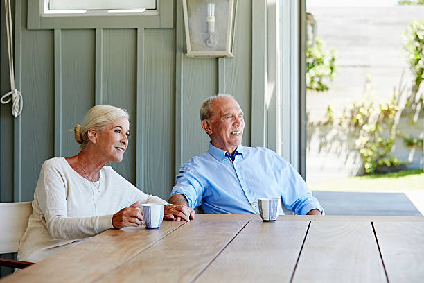 Couple de seniors qui boit un café sur sa terrasse ombragée