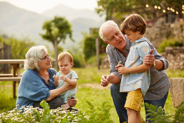 Couple de grands-parents qui jouent de le jardin avec leurs petits-enfants